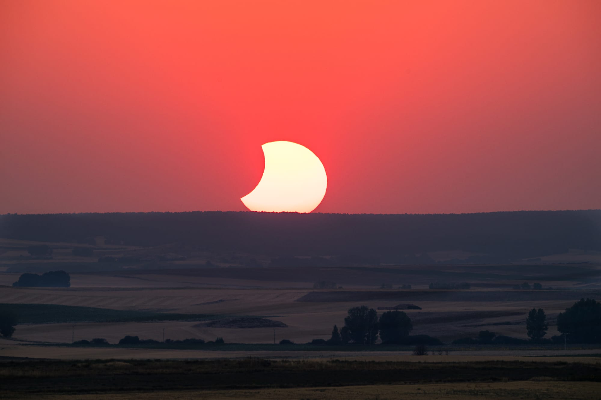 El Sol parcialmente eclipsado, a punto de ocultarse tras el horizonte del Campo de Gómara, en Soria